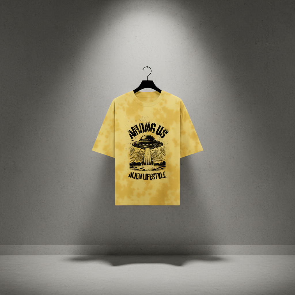 Yellow t-shirt with alien graphic and text on a hanger against a gray wall